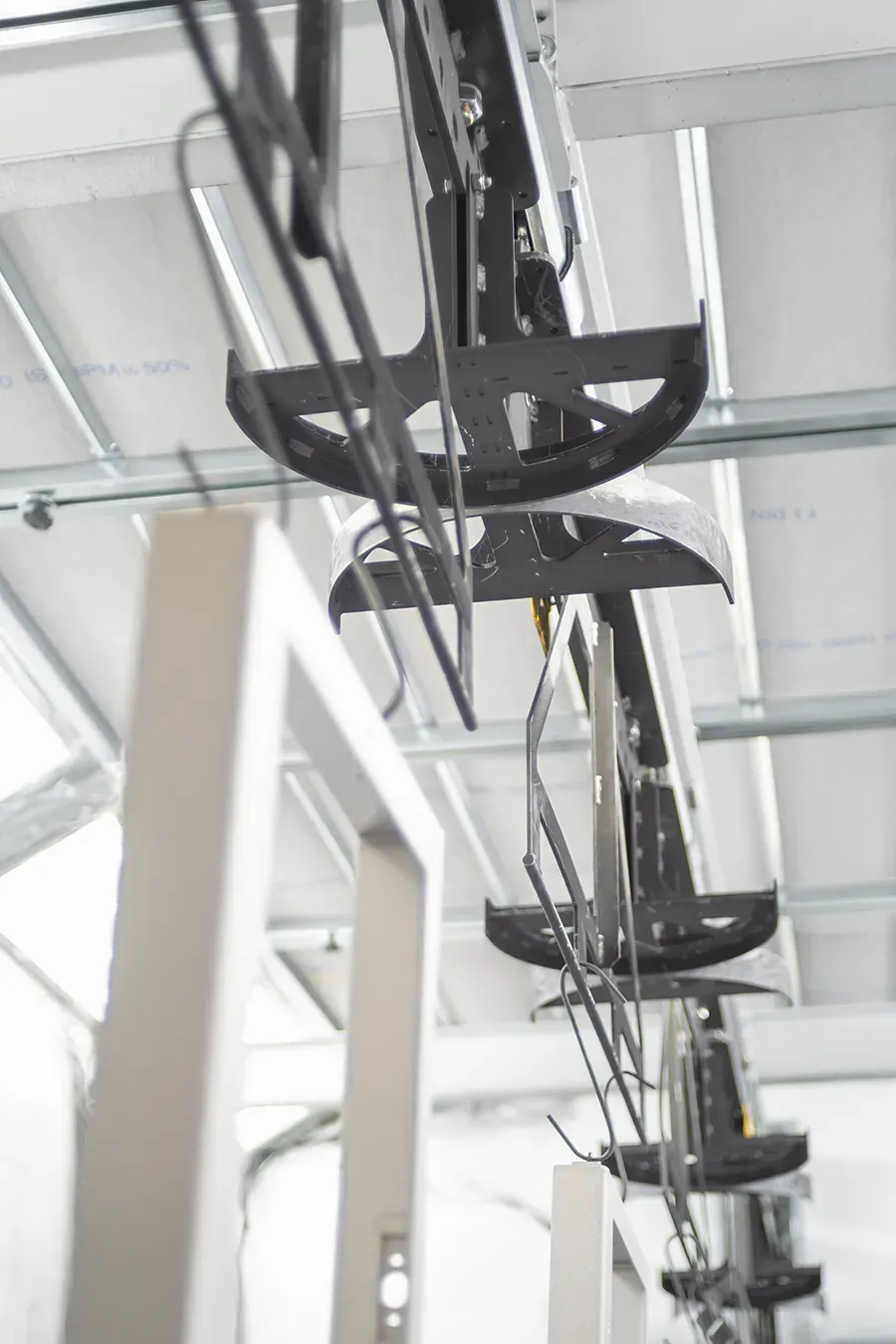 Metal parts on an overhead hanger in coating booth