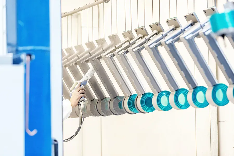 Metal parts in manual coating booth being coated