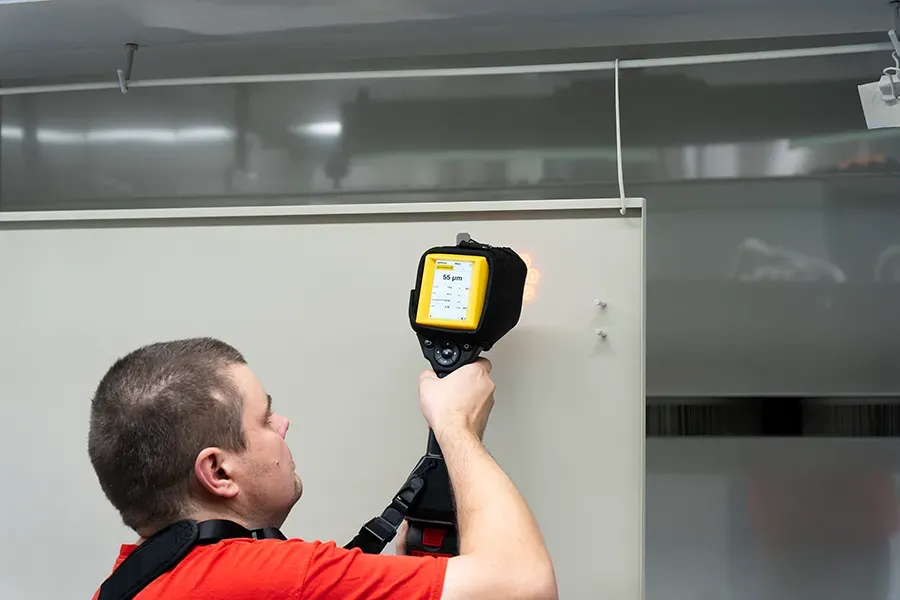 Pracovník lakovny měří nevytvrzenou vrstvu práškové barvy pomocí měřicího přístroje CoatMaster Flex