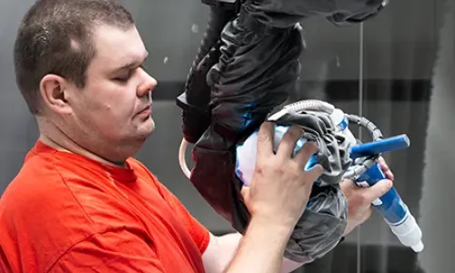 Muž operující robotický lakovací systém