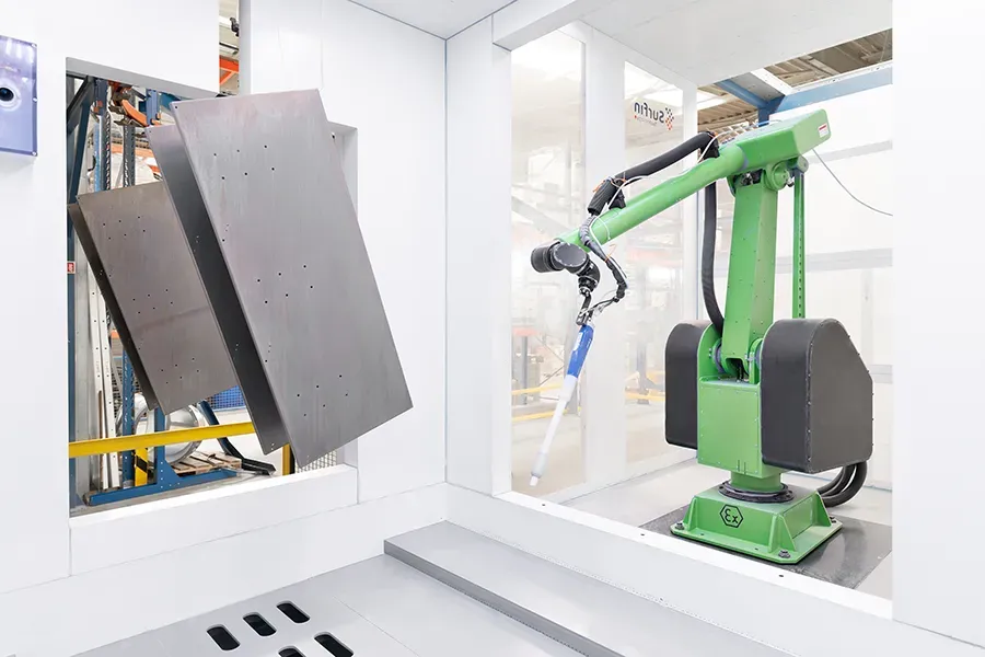 Metal parts on a conveyor with a coating robot arm at Triton