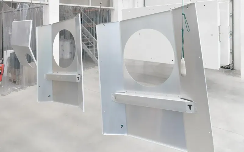 Metal parts hanging on a manual conveyor at Miroslavské strojírny