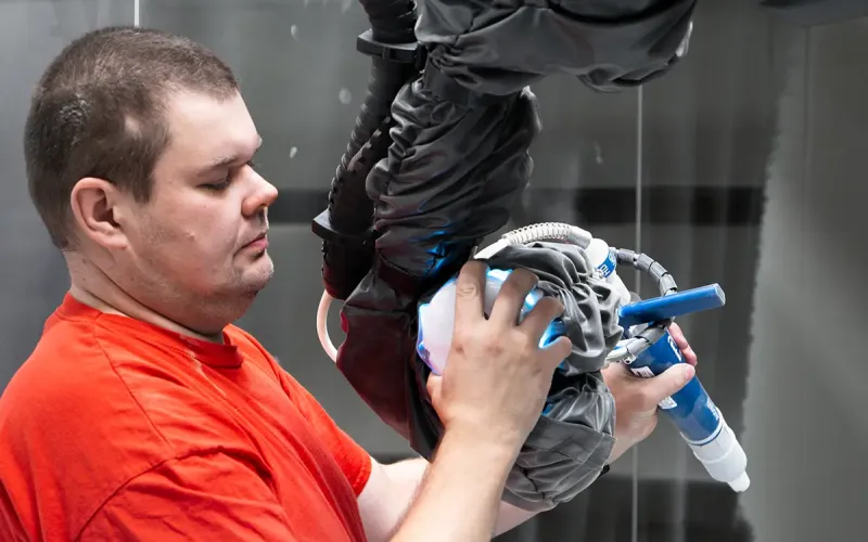 Muž držící robotickou paži s lakovací pistolí