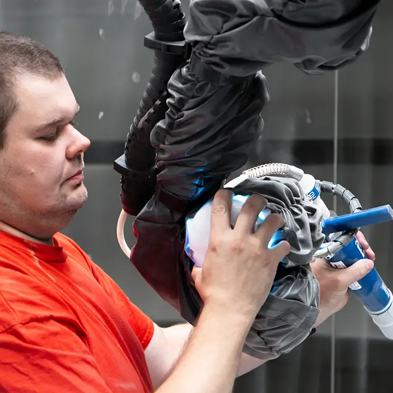 Muž držící robotickou paži s lakovací pistolí