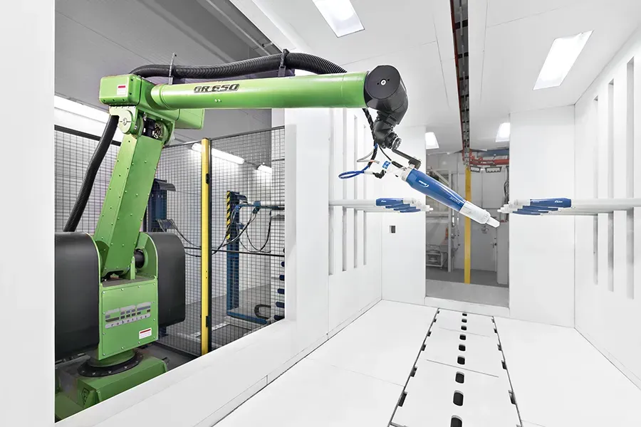 Green robotic arm in a coating booth at Kasi