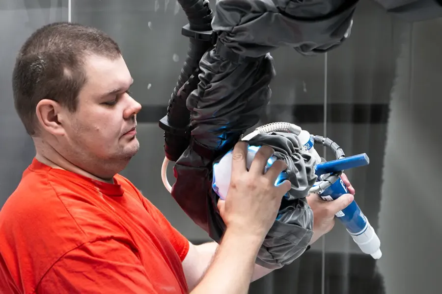 Muž držící robotickou paži s lakovací pistolí