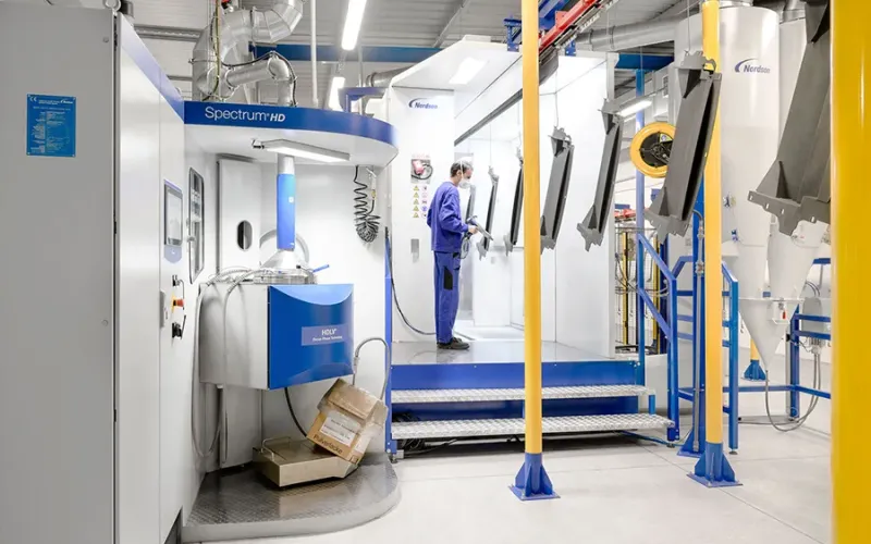Worker manually coating metal parts