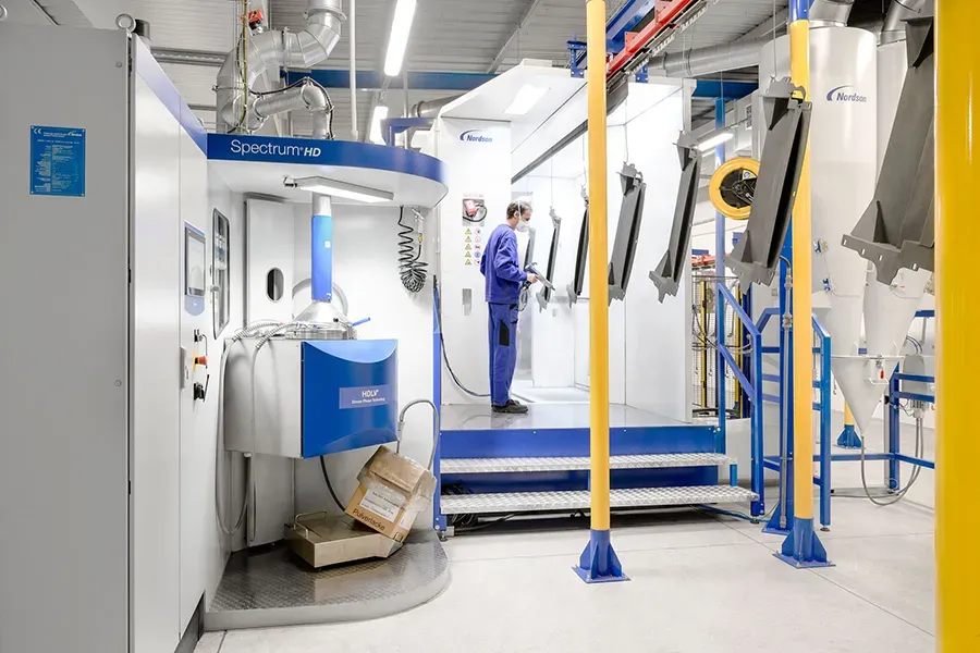 Worker manually coating metal parts